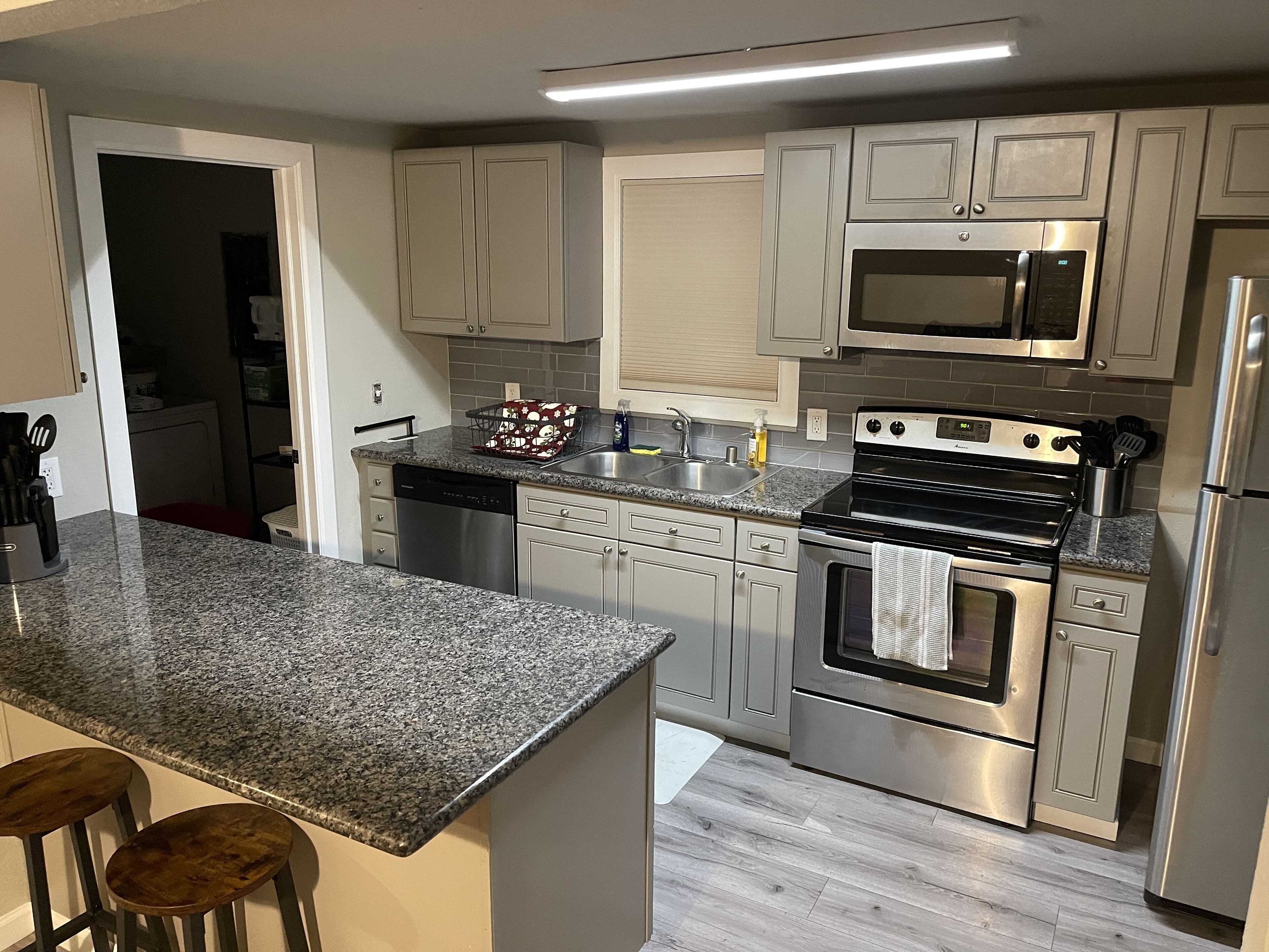 A modern kitchen with granite countertops, stainless steel appliances, and a central island with bar stools.