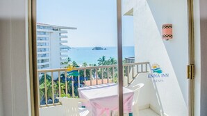 A balcony with a view of the sea and a building in the background. - Habitación Estándar vista Mar Enna Inn (Ixtapa)