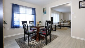 Un coin repas avec une table ronde, quatre chaises et un tapis à motifs.