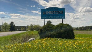 Une pancarte accueillante indiquant « aLimestone », avec un ciel dégagé et une route en arrière-plan.