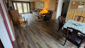 Un vaste espace de vie doté d’un plancher en bois, d’un canapé, d’une table basse et d’une table à manger avec des chaises.