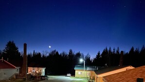 Une rue tranquille, la nuit, avec des maisons et une lune bien visible.