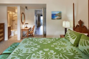 Een hotelkamer met een bed, een bureau, een stoel, een badkamer en uitzicht op zee.