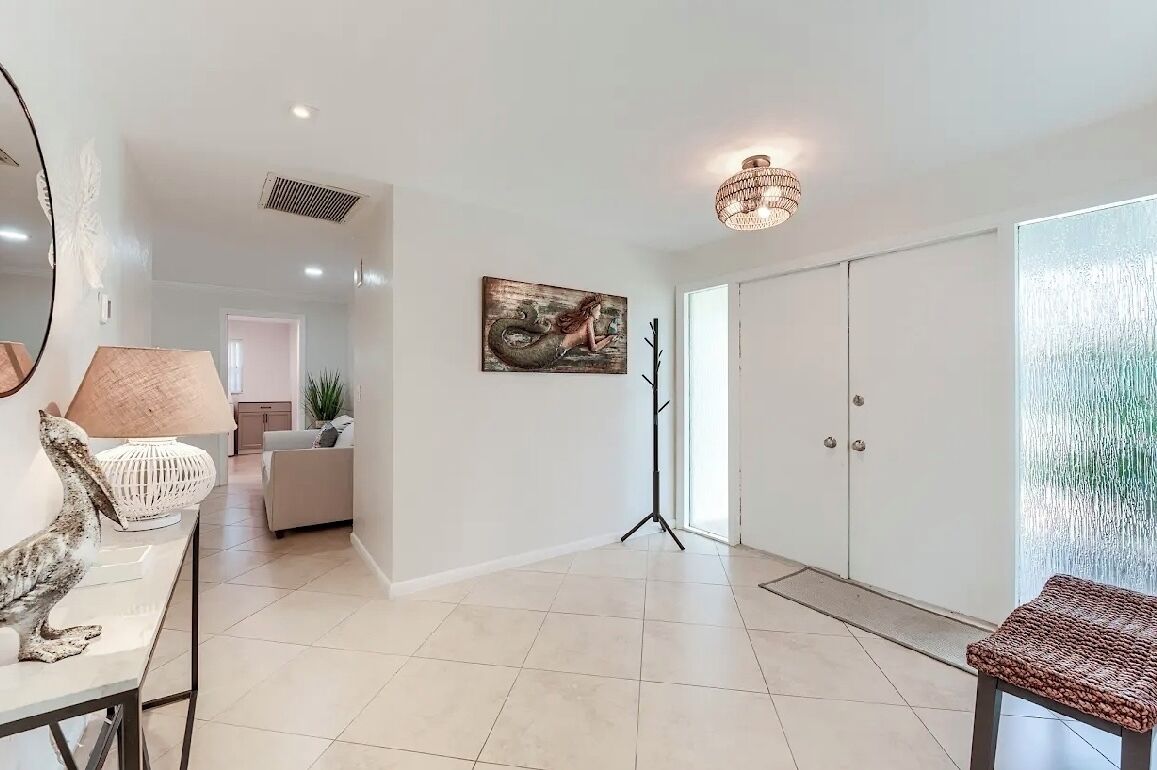 A spacious living area with a modern design, featuring a large mirror, a floor lamp, and a painting on the wall.