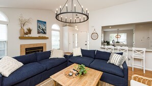 A living room with a dark blue sectional sofa, a wooden coffee table, and a fireplace. - Clean Coastal Cottage 5min to beach & 20 min to Charleston (Mount Pleasant)