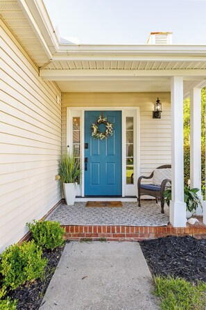 A house with a blue door, a porch with a bench, and a wreath on the door.