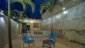 A patio area with two blue chairs, a small pool, and a stone wall. - La Ermita Suites in Merida Centro with Pool - Historic Church Front (Centro)