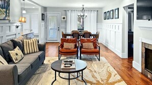 A living room with a sofa, coffee table, dining table with chairs, a fireplace, and a hallway leading to another room. - Pet Friendly, Walk to beach, pool and community dock and more! (Kiawah Island)