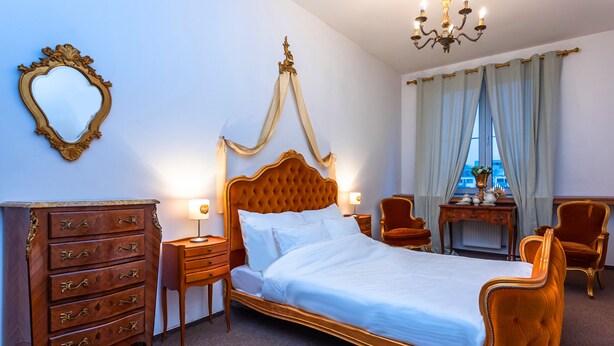 Un dormitorio con una cama con dosel, un aparador de madera, una tocador con espejo y una ventana con cortinas.