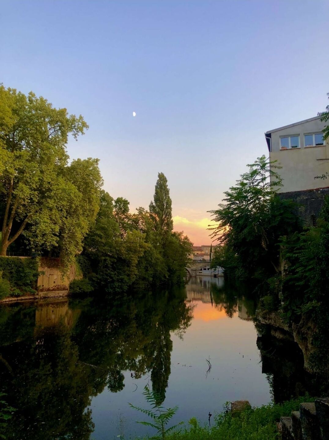 A calm river with trees and a building on the right.