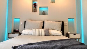 Un dormitorio moderno con una cama grande, dos mesitas de noche y tres lámparas fijadas a la pared.