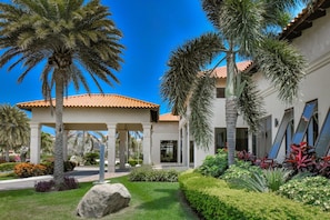 A modern building with a covered entrance, palm trees, and well-maintained landscaping. - Captivating 2BR Townhouse near Beaches in Aruba (Noord)