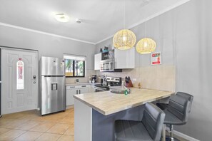 Una cocina moderna con una isla central, electrodomésticos de acero inoxidable e iluminación colgante.