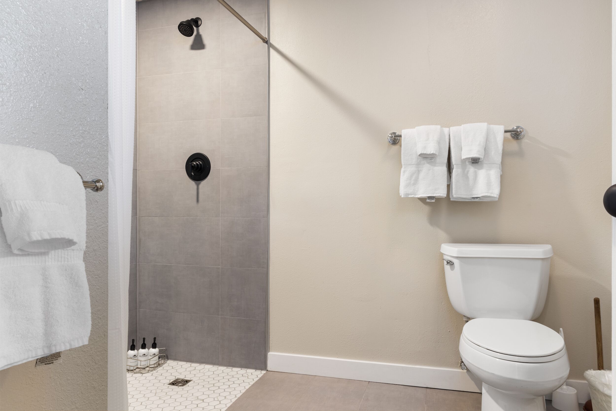 A bathroom with a shower, toilet, and towel rack.