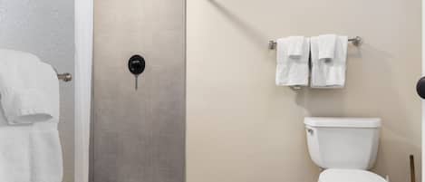A bathroom with a shower, toilet, and towel rack.