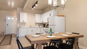 Eine moderne Küche mit weißen Schränken, einem Holztisch und schwarzen Stühlen.