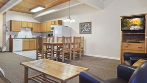 A modern kitchen with wooden cabinets, a dining area with a table and chairs, and a living room with a sofa and a television. - Outpost: Town Square Lodge 9 - Close to Town Square (Jackson)