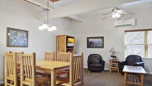 A dining area with a wooden table and chairs, a ceiling fan, and a TV. - Outpost: Town Square Lodge 9 - Close to Town Square (Jackson)