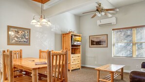 A dining area with a wooden table and chairs, a small wooden cabinet, and a ceiling fan.