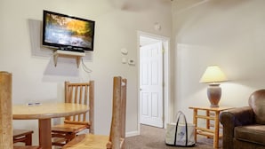 Ein Wohnzimmer mit Fernseher, Holzmöbeln, einer Lampe und einer Tür.
