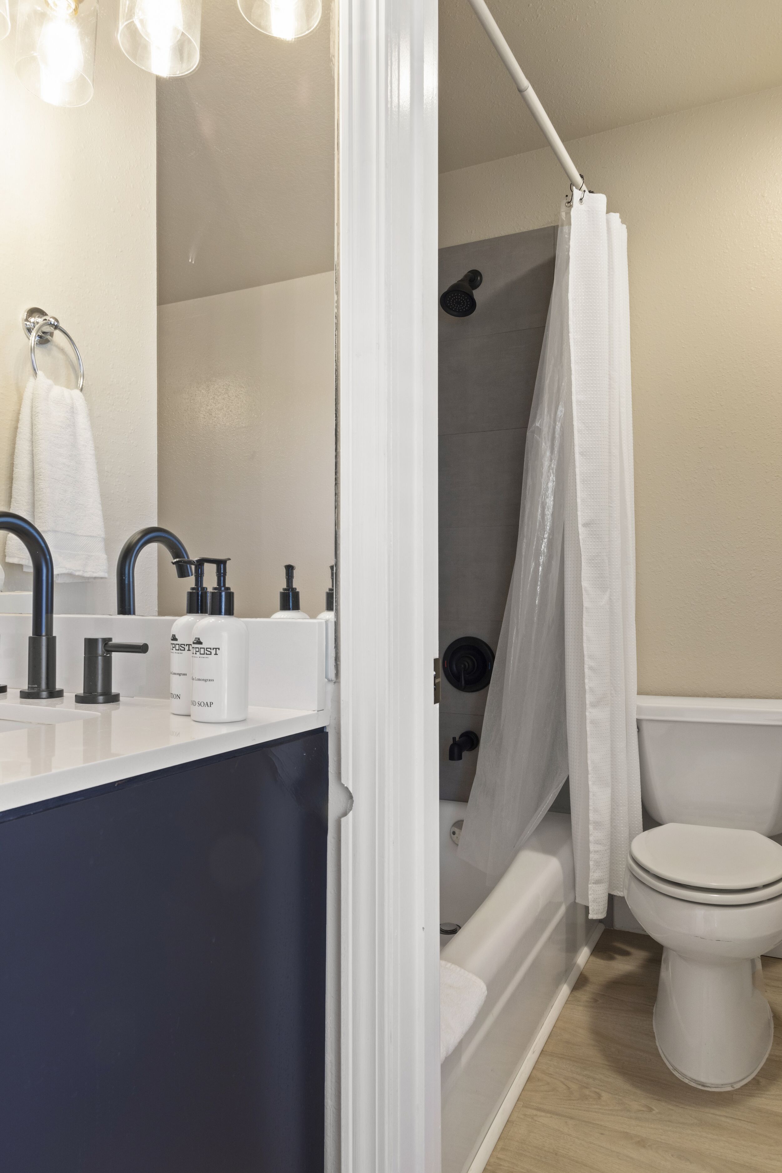 A modern bathroom with a white sink, black faucets, and a shower curtain.