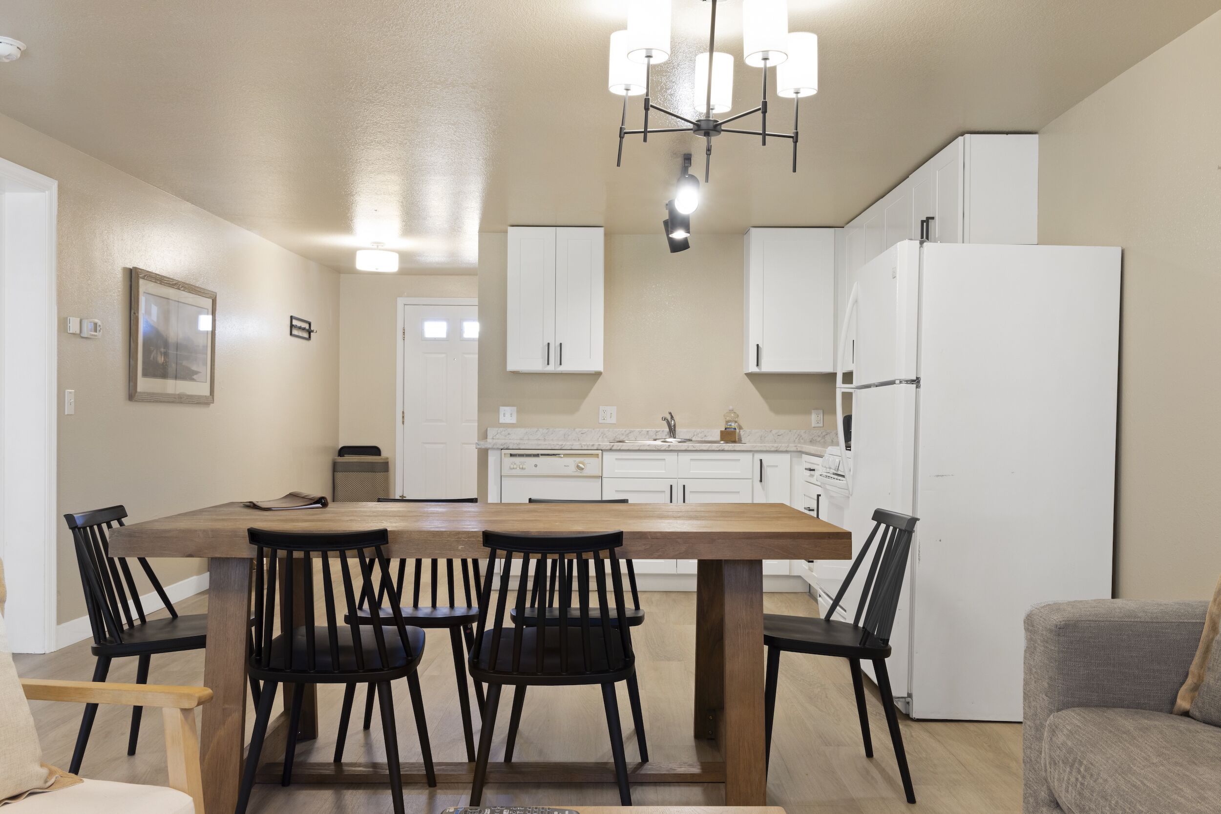 A modern kitchen with white cabinets, a wooden dining table, and black chairs.