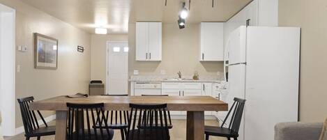 A modern kitchen with white cabinets, a wooden dining table, and black chairs.