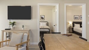 Et hotelværelse med et træspisebord, en enkeltseng, et natbord med en lampe og et fjernsyn ophængt på væggen.