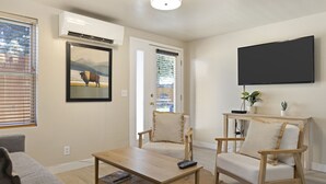 En stue med sofa, to stole, sofabord, et fladskærms-tv ophængt på væggen og et billede af en bison på væggen.