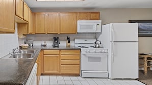 A kitchen with wooden cabinets, a white stove, a white refrigerator, a microwave, and a coffee maker. - Outpost: Town Square Lodge 6 - Close to Town (Jackson)
