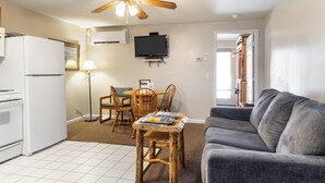 A compact living space with a kitchenette, a dining area, a gray sofa, and a ceiling fan. - Outpost: Town Square Lodge 6 - Close to Town (Jackson)