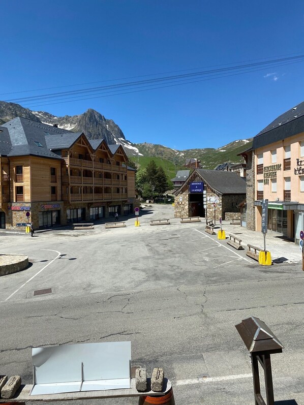 A mountain town with a wooden building with balconies, a stone building with a sign, and a clear sky.