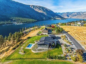 A residential area with houses, a swimming pool, and a lake with mountains in the background. - Private Pool | Stunning lake & mountain views | Modern, costal design (Manson)
