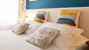 A neatly made bed with white linens and floral-patterned pillows, a blue accent wall, and a framed picture above the bed. - ELEGANT COZY 2BD IN SANTA CROCE - FLORENCE (FIRENZE)