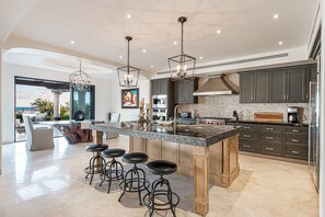 Cozinha moderna com uma ilha grande, banquetas e vista para o exterior.