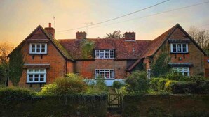 A traditional brick house with two chimneys, a gated entrance, and a brick wall. - A quirky character cottage on the edge of the New Forest (Totton)