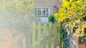 A wooden gate leading to a brick staircase with a house in the background. - A quirky character cottage on the edge of the New Forest (Totton)