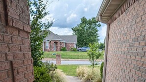 A brick pathway leading to a garage with a brick wall on one side and a grassy area on the other.