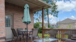 A covered patio with wicker furniture, a table, and an umbrella.