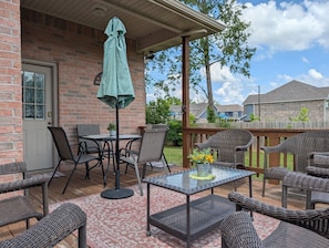 A covered patio with wicker furniture, a table, and an umbrella.