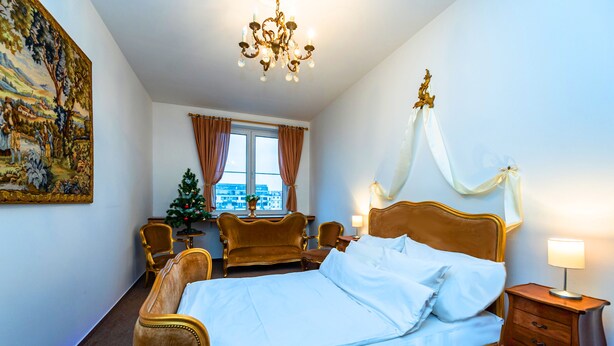 Een slaapkamer met een groot bed, een kroonluchter, een kerstboom en uitzicht op de stad.