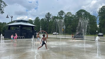 A water play area with multiple fountains and a gazebo in the background.