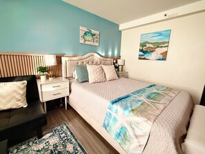 A bedroom with a bed, nightstands, a desk, a chair, and a decorative rug.