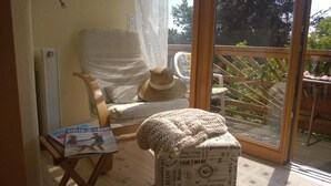 Una habitación acogedora con una silla de madera, un sombrero de paja y una manta tejida sobre una caja.