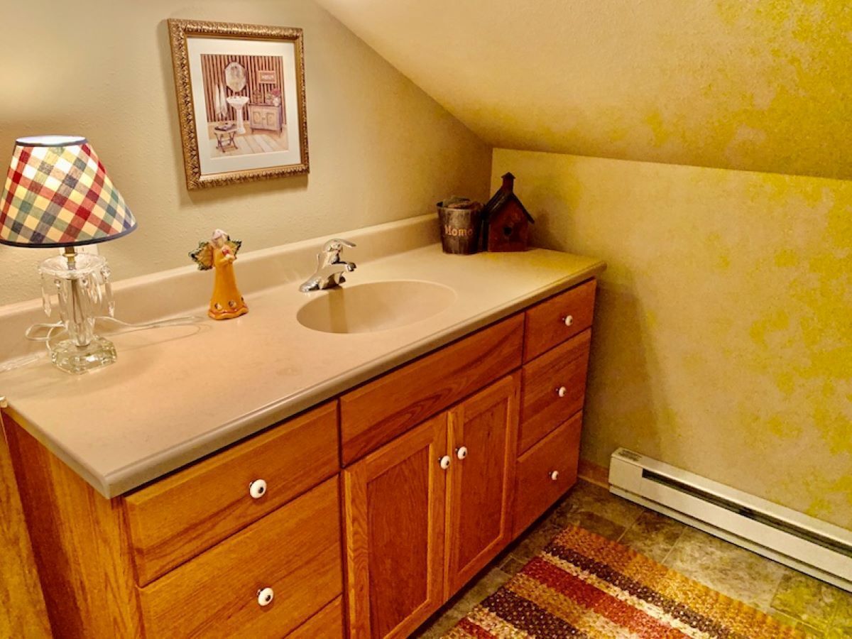 A bathroom with a wooden vanity, a sink, a mirror, and a radiator.