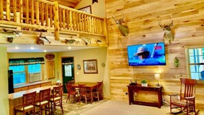 A wooden interior with a bar area, dining chairs, and mounted animal heads. - Log Cabin/ w hot tub, outdoor pool & pool table (Lansing)
