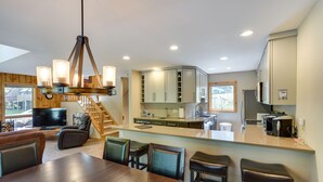 Una cocina moderna con una isla central, armarios empotrados y un comedor con una mesa y sillas de madera.