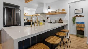 A modern kitchen with a large island, bar stools, and a built-in oven. - Corner Cabin • AC • Spa • Game room • Dog Friendly (Big Bear)