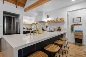 Een moderne keuken met een groot eiland, barkrukken en een inbouwoven.