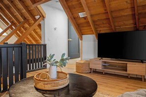 Ein modernes Wohnzimmer mit Holzboden, einem schwarzen runden Tisch, einem Fernseher und einem Korbwannen-Korb.